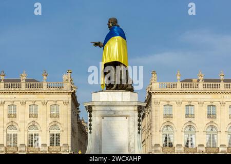 Frankreich, Meurthe et Moselle, Nancy, Stanislas-Platz (ehemaliger Königsplatz), erbaut von Stanislas Leszczynski, König von Polen und letzter Herzog von Lothringen im 18. Jahrhundert, von der UNESCO zum Weltkulturerbe erklärt, Fassaden des Opernhauses (links) und des Grand Hotel de la reine (rechts) und Statue von Stanislas mit der Flagge von Ukranien Stockfoto