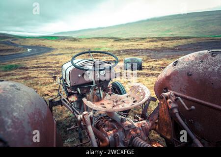 Rostiger Traktor mit gebrochenem Sitz und Lenkrad in schlechtem Zustand auf einer Weide in Island. Stockfoto