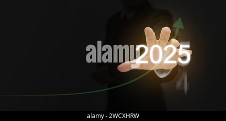Frohes neues Jahr 2025. Ein Mann streckt seine Hand aus, um 2025 neue Möglichkeiten zu nutzen, mit einer steigenden Kurve, die die Erwartung einer produktiveren Entwicklung symbolisiert Stockfoto