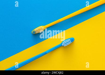 Zahnbürsten auf gelbem und blauem Hintergrund. Gesundheitskonzept. Stockfoto
