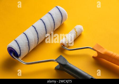 Große und kleine Malerwalze auf gelbem Hintergrund. Hausrenovierungskonzept. Stockfoto