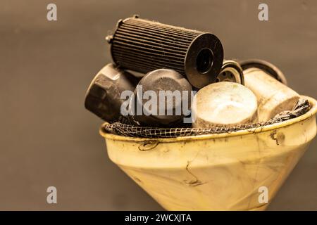 Foto von alten, erschöpften Ölfiltern in einer Werkstatt als Symbol für die Entsorgung gefährlicher Abfälle in der Fahrzeugwartung. Stockfoto