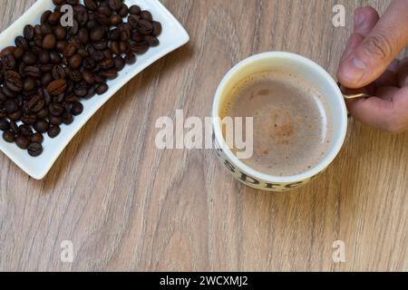 Halten Sie eine Tasse Kaffee mit Kaffeebohnen auf einer Seite Stockfoto