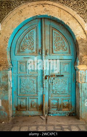 Eine alte türkisfarbene Bogentür mit Berbersymbolen im Herzen der alten Medina in Kairouan, Tunesien. Kairouan ist der 4. Heiligste ci Stockfoto