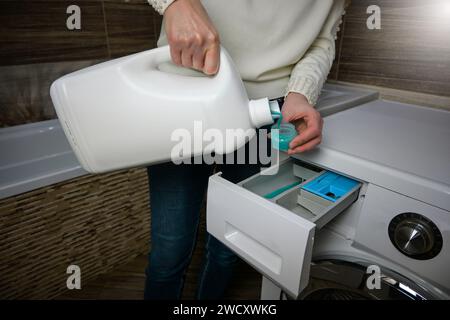 Eine Frau gießt Waschmittel in die Waschmaschine. Stockfoto