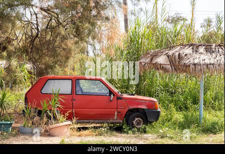 Altes verlassenes Auto in einem verwachsenen Garten an einem hellen Sommertag Stockfoto