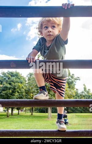 Ein kleiner Junge klettert auf eine hölzerne Leiter Stockfoto