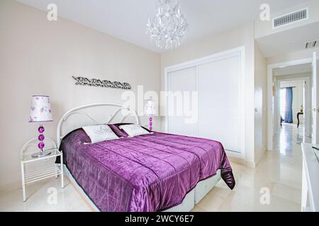 Ein Gästezimmer mit lila Decken und Dekorationen im Ferienhaus Stockfoto