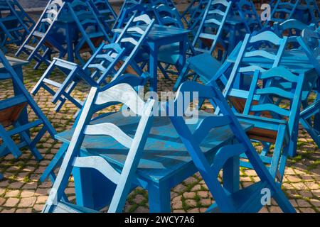 Leere blaue Holztische und -Stühle vor einem Café oder Restaurant, gestapelt. Stockfoto