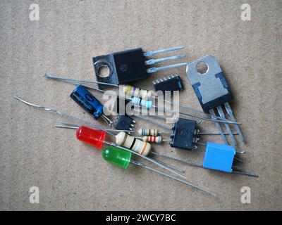 Gemischte elektronische Schaltungskomponenten. Halbleiter (integrierte Schaltungen, Transistoren, LEDs), Widerstände und Kondensatoren befinden sich auf der Werkbank. Stockfoto