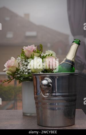 Rosenbusch und Sektkühler mit offener Sektflasche Stockfoto