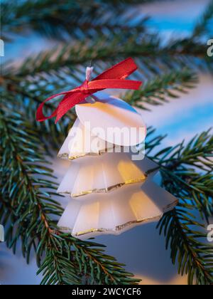 Weiße aromatische Kerze in Form eines dekorativen Weihnachtsbaums auf einem Tannenzweig in Nahaufnahme Stockfoto