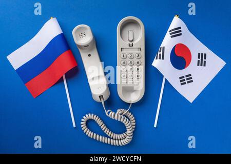 Altes Telefon und zwei Flaggen auf blauem Hintergrund, Konzept zum Thema Telefongespräche zwischen Südkorea und Russland Stockfoto