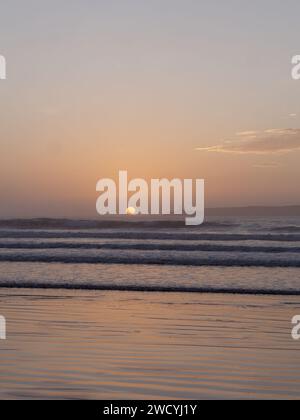 Ruhige Szene, wenn die Sonne am Horizont untergeht, neben einer Insel, während die Wellen hereinbrechen, in Essaouira, Marokko, 17. Januar 2024 Stockfoto