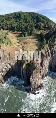 Ein schmaler Wasserfall stürzt von einer beeindruckenden Klippe in der Nähe des Neahkahnie Aussichtspunkts entlang der zerklüfteten Küste Oregons zwischen Cannon Beach und Tillamook. Stockfoto