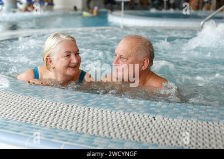 Glückliches älteres Paar, das Hydromassage im Swimmingpool im Spa genießt. Urlaubskonzept. Stockfoto