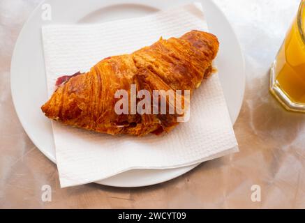 Art servierte Vorspeise auf Teller - zartes Blätterteigcroissant mit dünnen Schinkenscheiben in der Mitte Stockfoto