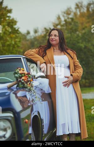 Vejle, Dänemark, 26. Oktober 2023: Schwangere Frau in der Nähe eines Retro-Autos Stockfoto