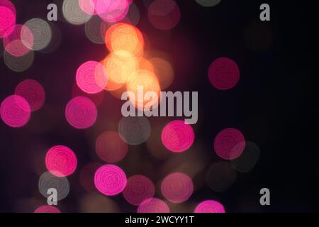 Abstrakter Unschärfe-Bokeh-Hintergrund. Silberweißes, rotes Bokeh-Licht auf unscharfem schwarzem Hintergrund Stockfoto