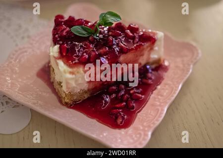 Teller mit köstlicher Käsekuchenscheibe mit Granatapfelmarmelade. Leckerer Käsekuchen. Draufsicht. Stück eines klassischen New Yorker Käsekuchens. Selektiver Fokus, Stockfoto