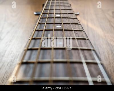 Hintergrund mit einem musikalischen Motiv, das einen Gitarrenhals darstellt. Geringe Schärfentiefe. Brauntöne. Stockfoto