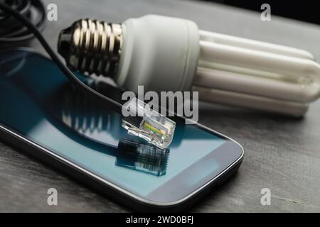 Energiesparlampe, Smartphone und Netzstecker, symbolisches Bild für Smart Home Stockfoto