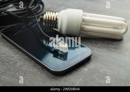 Energiesparlampe, Smartphone und Netzstecker, symbolisches Bild für Smart Home Stockfoto