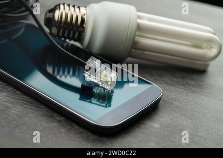 Energiesparlampe, Smartphone und Netzstecker, symbolisches Bild für Smart Home Stockfoto