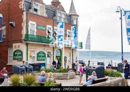 Fish and Chips Take-away Restaurant, The Parade, wo Leute draußen essen, Swanage an der Küste von Dorset, England, Großbritannien, 2023 Stockfoto