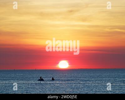 Blick auf einen spektakulären, lebendigen roten Sonnenuntergang über dem Meer und Horizont, aus Sicht von St Kilda Beach, Melbourne, Australien Stockfoto