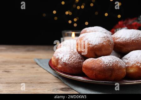 Köstliche süße Brötchen auf Holztisch vor schwarzem Hintergrund mit verschwommenem Licht, Platz für Text Stockfoto