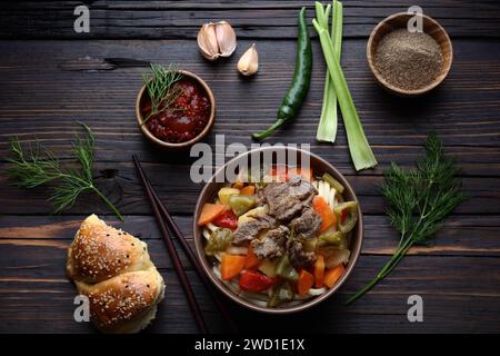 Usbekische Speisen mit Nudeln, Gemüse und Gewürzen Lagman. Uigurischer Lagman mit nicht gekochtem Gemüse. Serviert auf hölzernem Hintergrund Stockfoto
