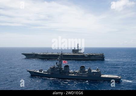 Das japanische Schiff JS Sazanami ist an der Seite der USS Ronald Reagan unterwegs. Stockfoto