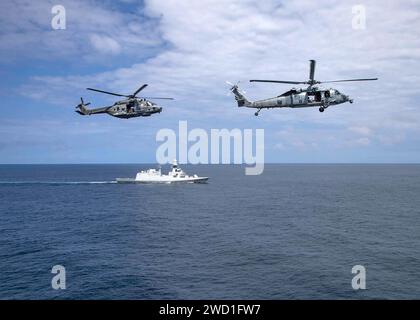 Ein MH-60S Seahawk und ein italienischer NH 90 Hubschrauber fliegen über die italienische Fregatte Federico Martinengo. Stockfoto