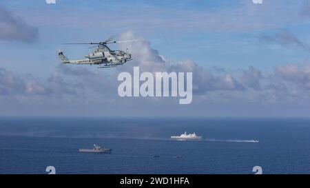 Ein Hubschrauber des U.S. Marine Corps AH-1Z Viper fliegt über Schiffen der U.S. Navy und der Republik Singapur im Südchinesischen Meer. Stockfoto