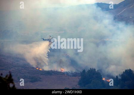 Ein Feuer- und Rettungshubschrauber Bell 205 A1 lässt Wasser fallen, um einen Brand zu löschen. Stockfoto