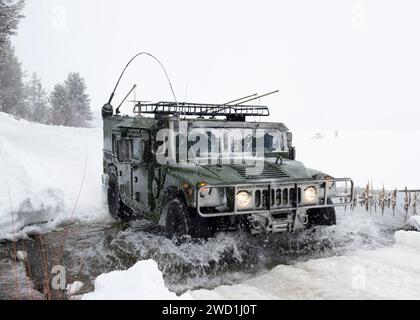 Ein Militärfahrzeug überquert einen Fluss bei schneebedecktem Wetter. Stockfoto