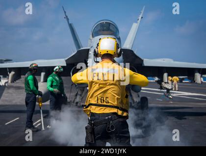 Aviation Boatswain's Mate leitet den Piloten einer F/A-18C Super Hornet an Bord der USS Carl Vinson. Stockfoto