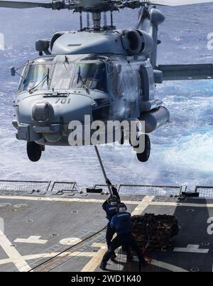 Seeleute üben das Anbringen von Paletten an einem MH-60R Sea Hawk Hubschrauber an Bord der USS Wayne E. Meyer. Stockfoto