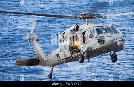 Ein MH-60S Sea Hawk Helikopter transportiert Fracht während einer Auffüllung auf See. Stockfoto