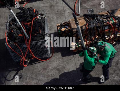 Seeleute haken Paletten an einen MH-60S Sea Hawk Hubschrauber während einer Auffüllung auf See. Stockfoto