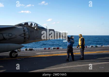 Die Fluggesellschaft Boatswain's Mate verwendet ein Jet Board, um mit dem Piloten einer AV-8B Harrier II zu kommunizieren Stockfoto