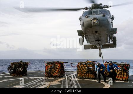 Seeleute verbinden Fracht mit einem MH-60S Sea Hawk Hubschrauber auf dem Flugdeck der USS Lake Champlain. Stockfoto
