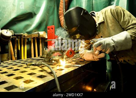 Der Feuerwehrmann für die Rumpfwartung schweißt zwei Metallteile zusammen. Stockfoto