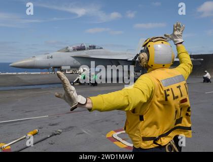 Die Fluggesellschaft Boatswain's Mate leitet ein F/A-18F Super Horne zu einem Katapult auf der USS Nimitz. Stockfoto