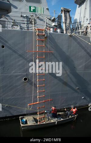 Seeleute bemalen die Wasserlinie des Schiffes an Bord der USS Carney, während sie im Hafen von Faslane in Schottland sind. Stockfoto