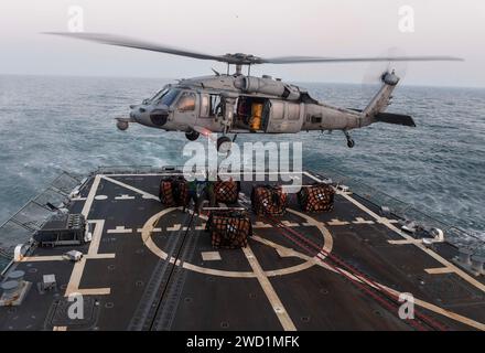 Seeleute befestigen den Palettenhaken an einem MH-60S Sea Hawk Hubschrauber an Bord der USS Wayne E. Meyer. Stockfoto