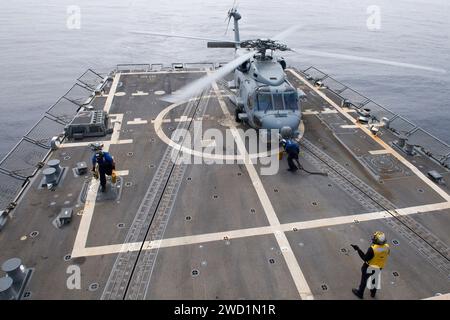 Seeleute entfernen Keile und Ketten von einem MH-60R Sea Hawk an Bord der USS Sterett. Stockfoto