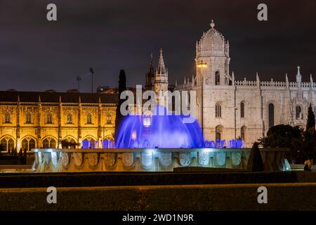 Kloster Jeronimos und Kirche Santa Maria de Belem bei Nacht in Lissabon, Portugal. Blick vom Garten Prac do Império mit beleuchtetem Brunnen. Stockfoto