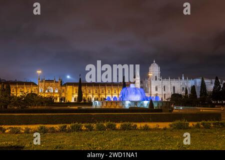 Kloster Jeronimos und Kirche Santa Maria de Belem bei Nacht in Lissabon, Portugal. Blick vom Garten Prac do Império mit beleuchtetem Brunnen. Stockfoto